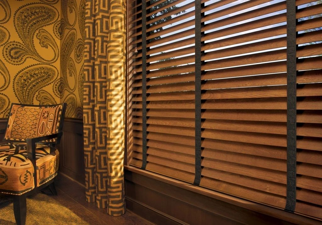 A wooden window with blinds and curtains in the corner.