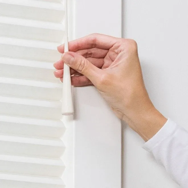 A person is opening the blinds on a window.