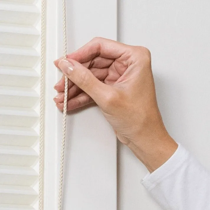 A hand is holding the handle of a window.