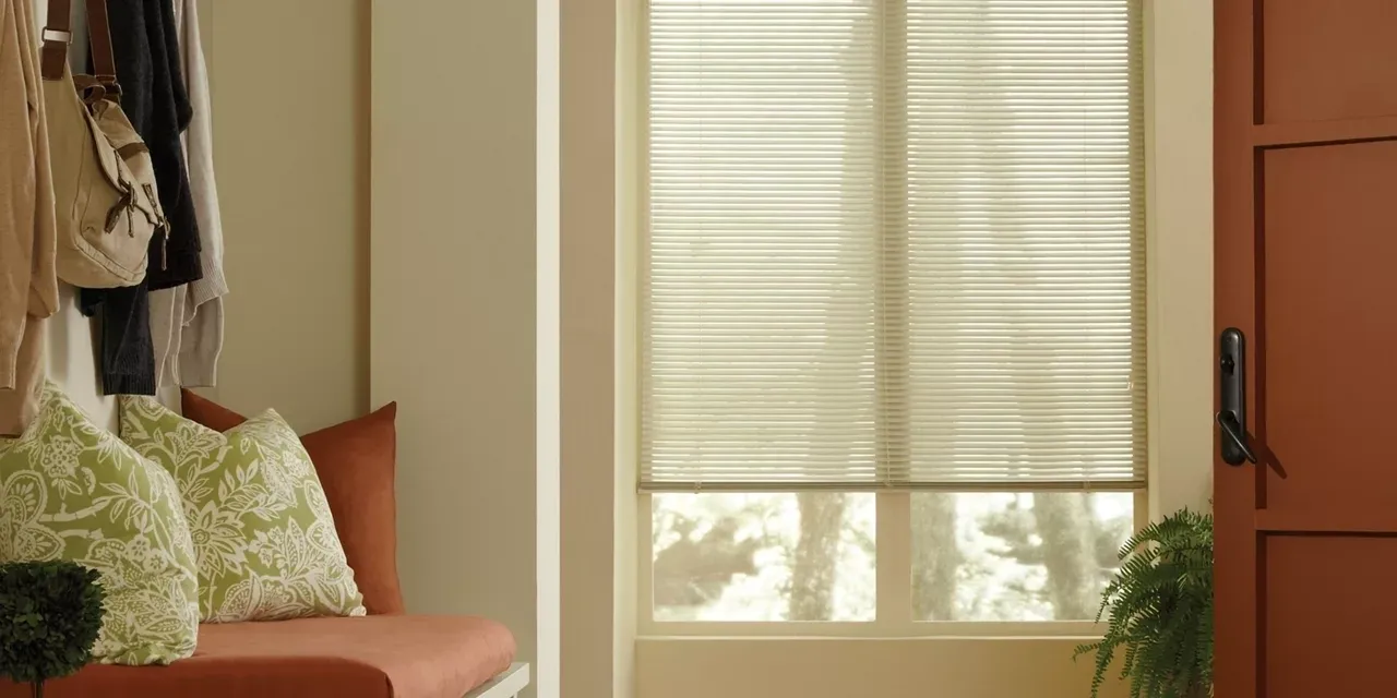 A room with a chair and window covered in blinds.